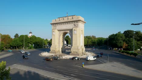 Side-View-Of-The-Arch-of-Triumph-in-Bucharest,-Romania-At-Sunrise-With-Traffic-Slowly-Moving