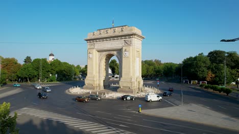 side view of the arch of triumph in bucharest, romania at sunrise with traffic slowly moving