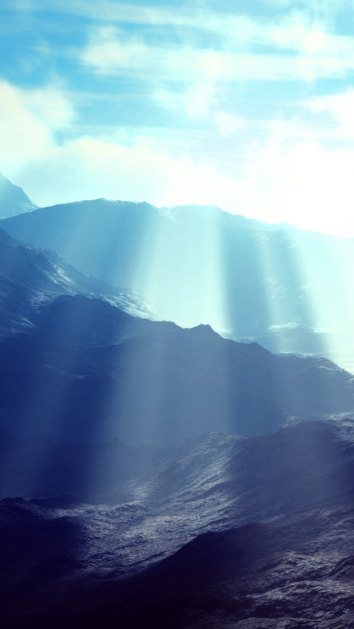 Ocean waves reflect sun rays over distant mountains during a clear day