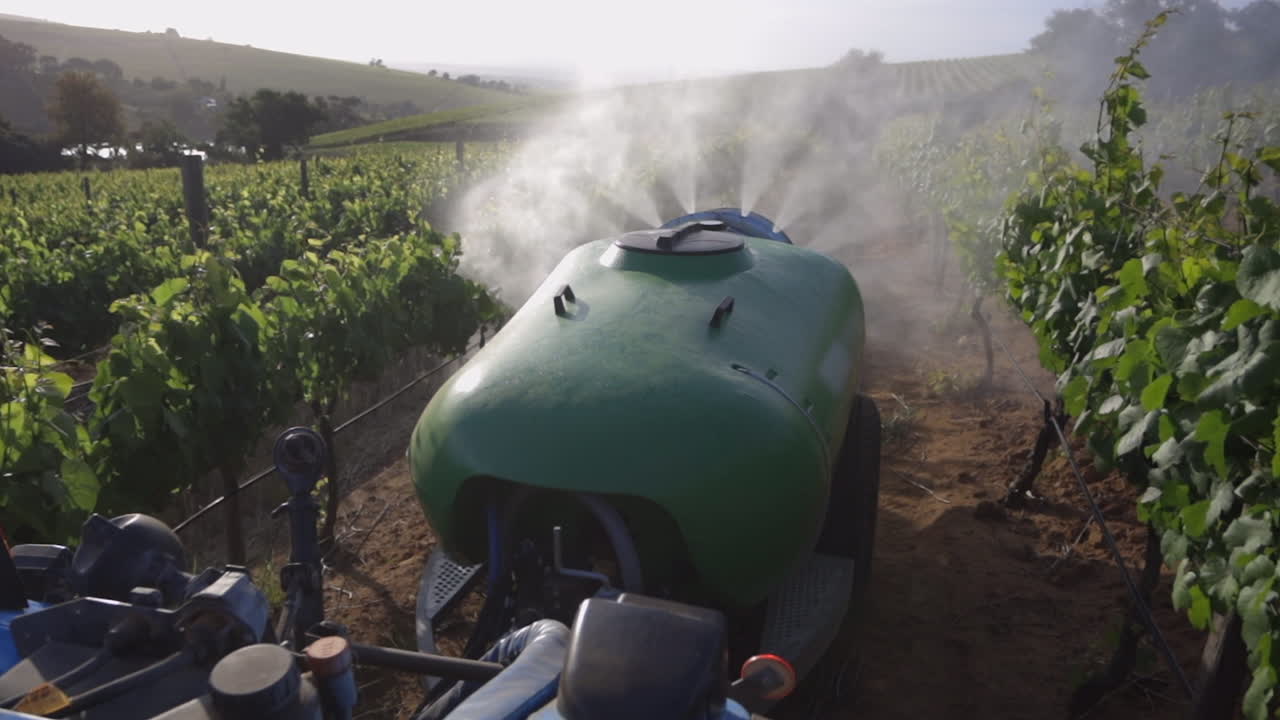 Bomba em tanque químico pulveriza pesticida nas videiras em um vinhedo.