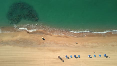 aerial shot over a beach of yellow sand and transparent turquoise water in malgrat de mar, province of barcelona flight over hammocks and deckchairs