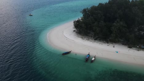 Traditionelle-Thailändische-Schiffe,-Die-Am-Wunderschönen-Weißen-Sandstrand-Und-Dem-Klaren-Blauen-Meer-Festmachen,-Während-Touristen-Ihren-Sonnenurlaub-Am-Strand-Von-Ko-Poda-Genießen