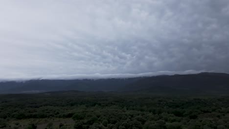 dark mammatus clouds loom over the lush tiétar valley and surrounding mountains in ávila, spain. aerial view shows dramatic spring contrast between vibrant landscape and stormy sky in may
