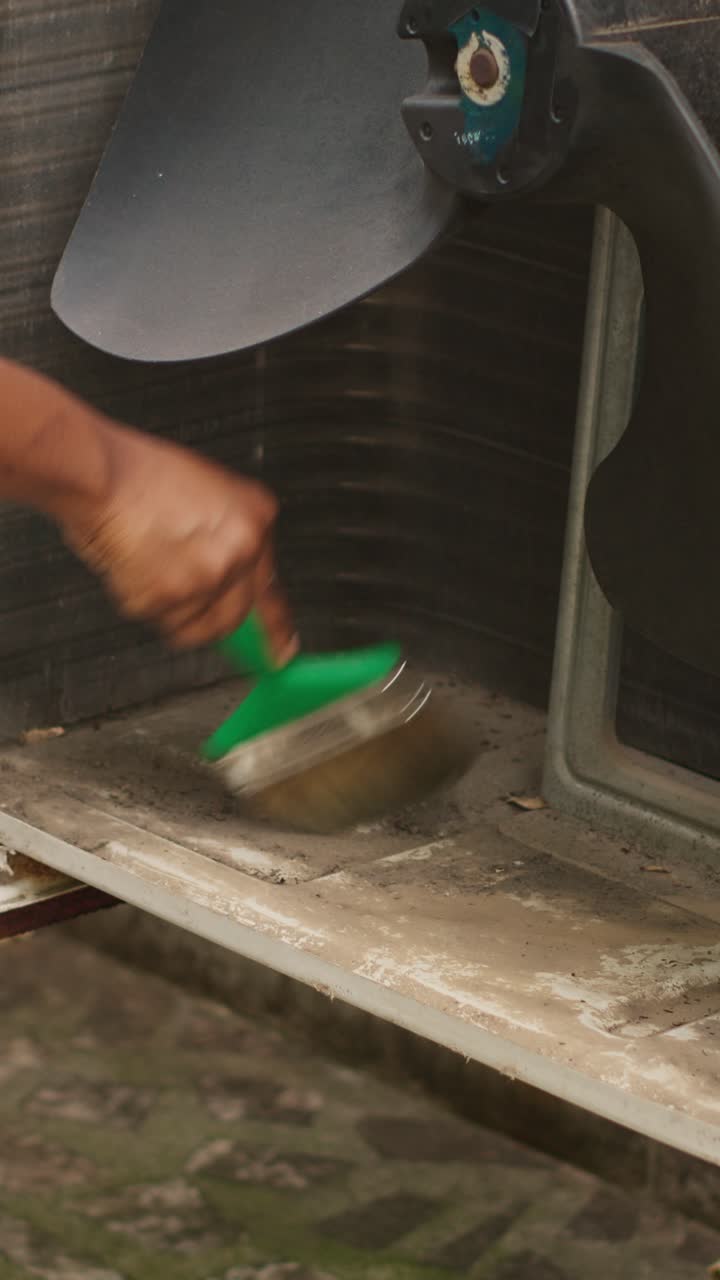 Vertical video Mechanic sweeping debris in HVAC unit