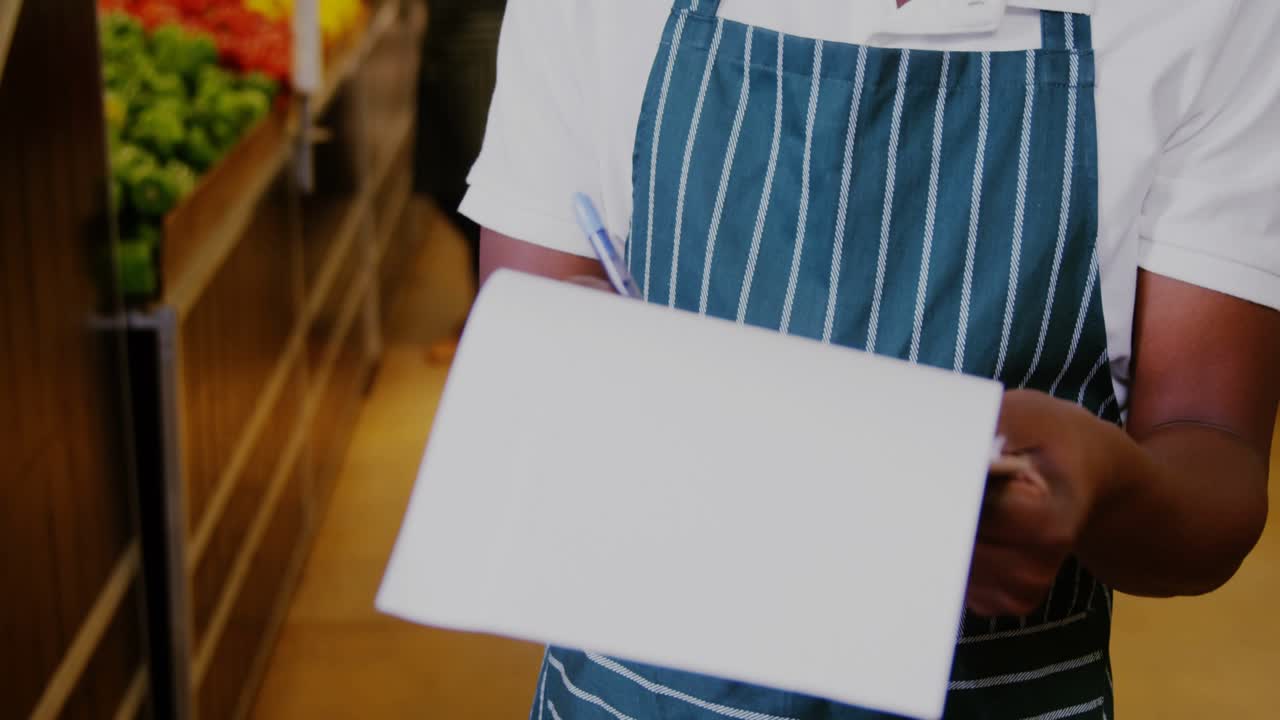 Supermarkedsmedarbejder tager noter, smiler mens grøn dataoverlay intensiverer friskhedsovervågningen.