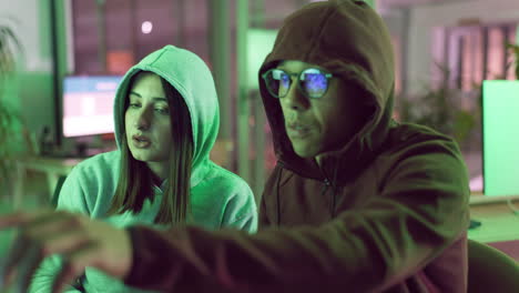 two young people working on computer at night