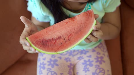 a young girl enjoys a slice of watermelon.