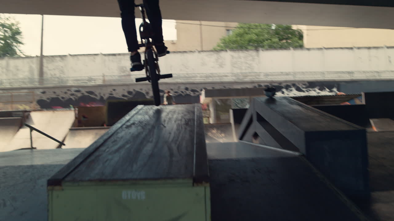 habilidades de entrenamiento de jinete bmx activo en el skatepark. motociclista corriendo en la rampa.