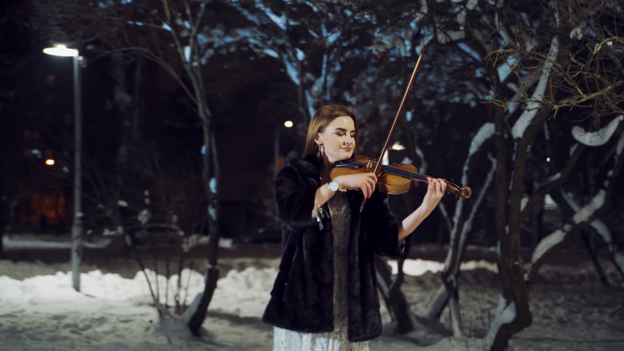 Girl performing music on city street. Portrait of woman perform music on violin in park outdoor