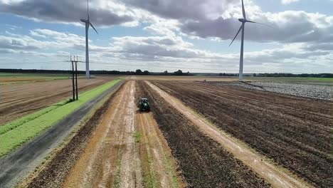 aerial view of tractor in field with wind turbines
