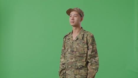 Side View Of Asian Man Soldier Looking Around While Standing In The Green Screen Background Studio
