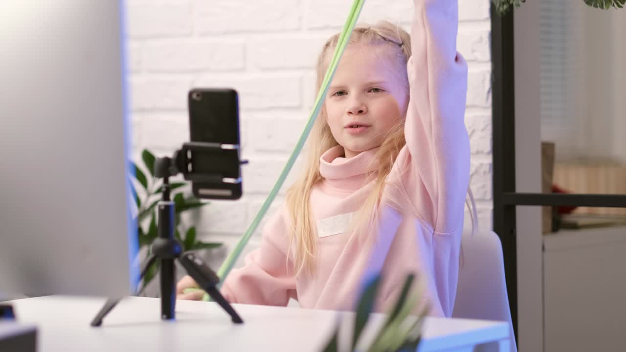 Pequena blogueira influenciadora conversando com seguidores em transmissão ao vivo, brincando com slime verde. Brinquedo líquido da moda esticando para o lado. Criança olhando para a tela do smartphone em casa. Câmera lenta