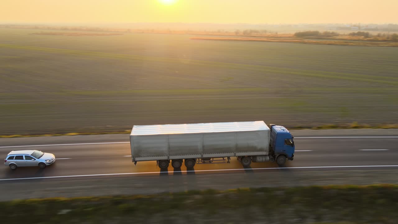 Vista aerea di un autoarticolato con rimorchio merci che viaggia in autostrada trasportando beni di sera. Concetto di trasporto e logistica delle consegne.