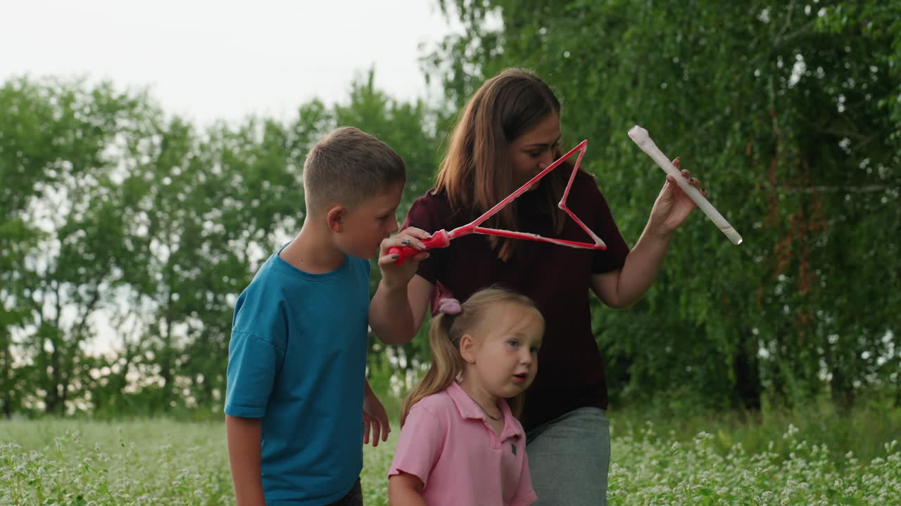 Family outdoor play, Mother and children enjoy sunny day, Mother and kids making bubbles amidst warm summer outdoors, Joyful family moment as mother teaches kids to blow bubbles outside