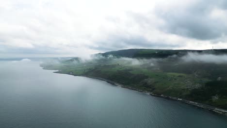 aerial view over the beautiful landscape of northern ireland on the coastal road near glenarm town overlooking the calm blue sea on a beautiful cloudy morning