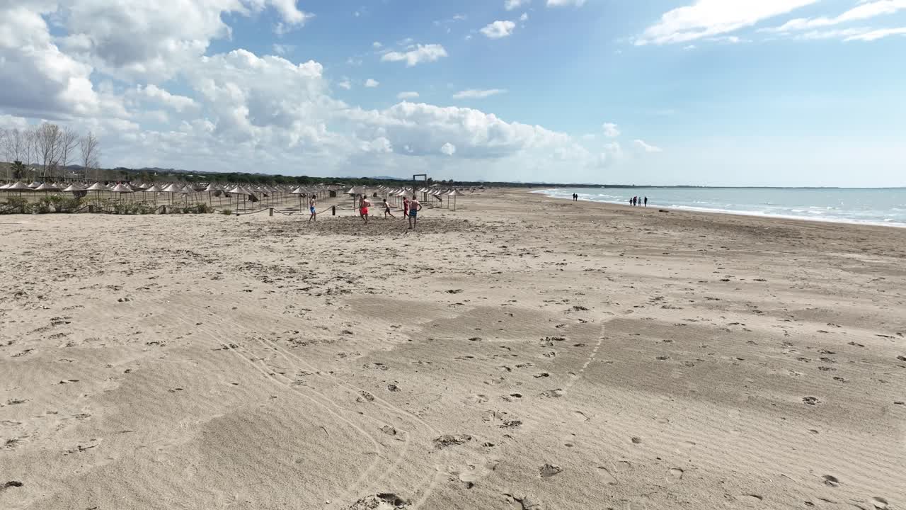 un grupo de amigos jugando con una pelota en la playa cerca del mar