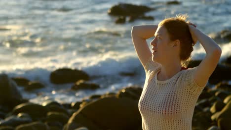 mujer de pie con las manos en el cabello en la playa 4k
