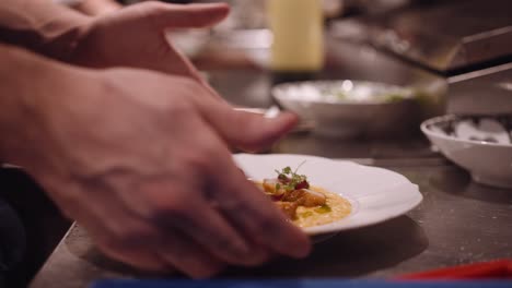 el cocinero masculino termina el plato de pasta y lo pasa para que se sirva en un restaurante