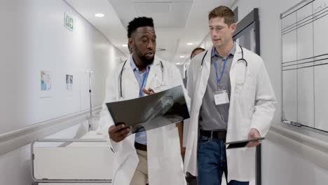 Serious-diverse-male-and-female-doctors-talking-and-walking-with-x-ray-in-slow-motion,-unaltered