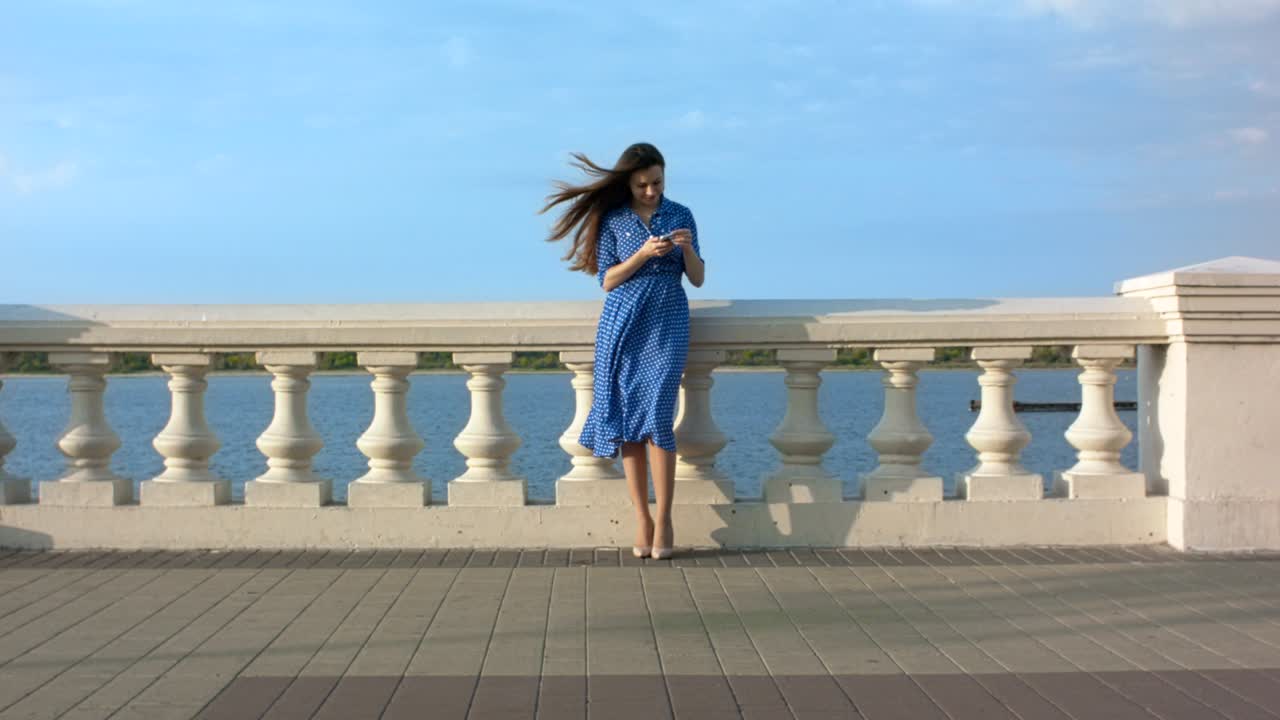 웃는 젊은 여성이 전화로 문자 메시지를 보내고 있습니다.