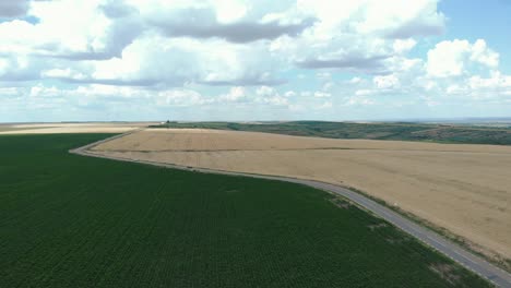 Aerial-View-Over-Country-Road-Through-Agricultural-Fields---drone-shot