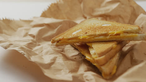 video de primer plano de sándwiches de queso tostado en papel marrón sobre un fondo gris