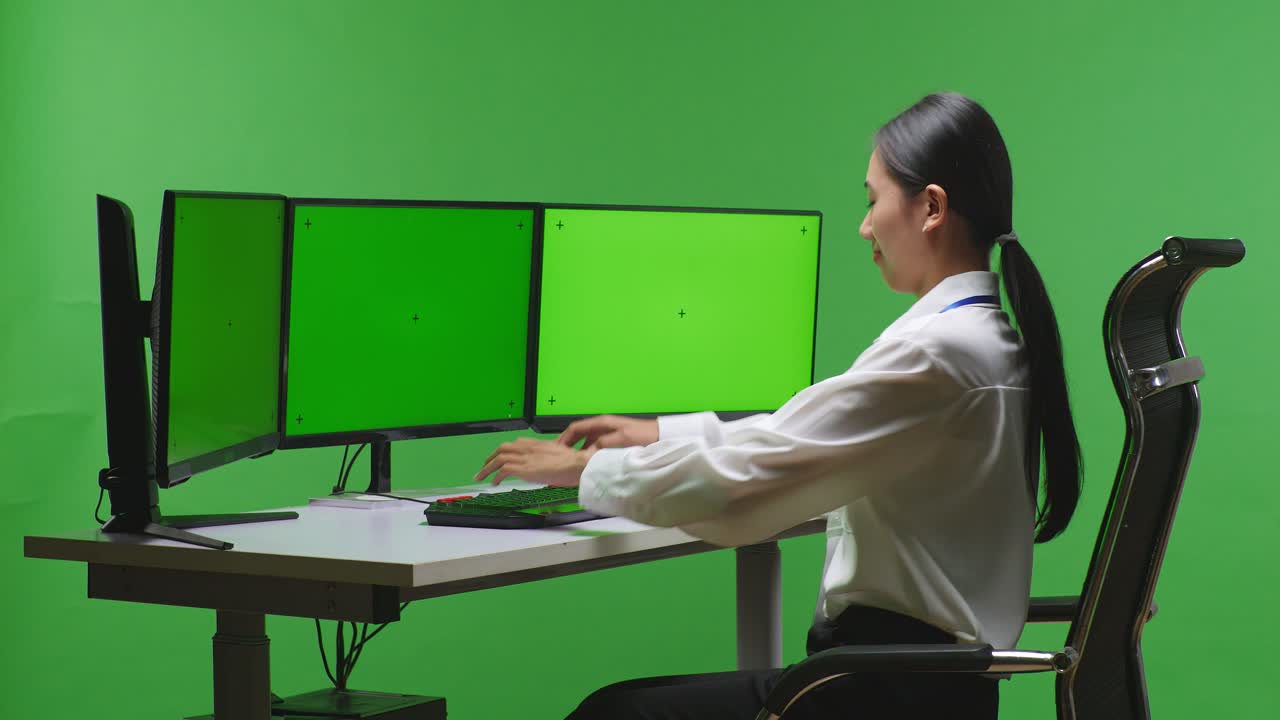 여러 개의 모니터를 가진 컴퓨터에서 일하는 여성
