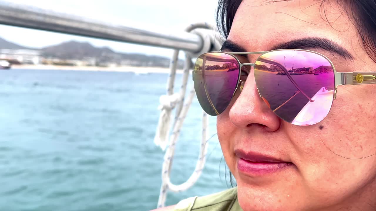 mujer atractiva con gafas de sol reflectantes disfrutando de un paseo en barco en un destino tropical