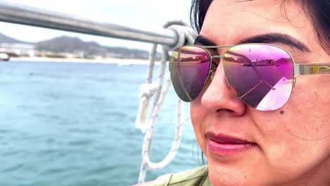 mujer atractiva con gafas de sol reflectantes disfrutando de un paseo en barco en un destino tropical