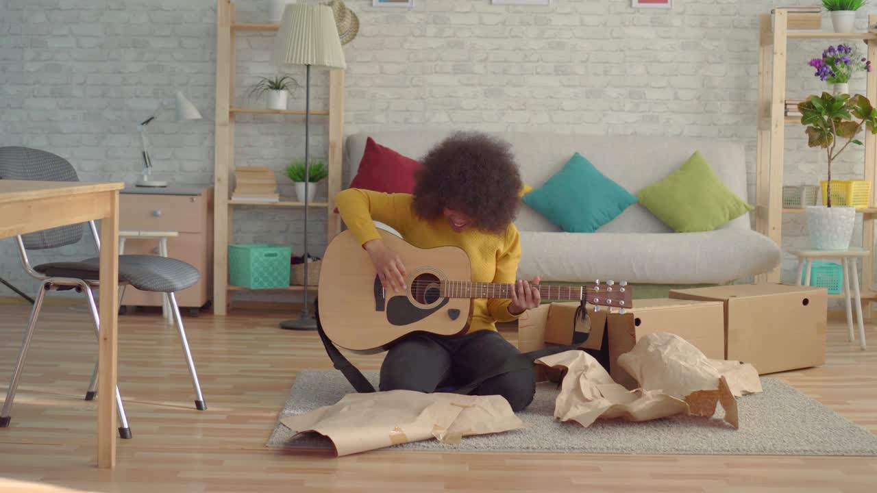 african american woman with an afro hairstyle unpacks a new guitar