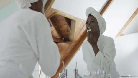 mujer afroamericana atractiva quitando el maquillaje en el baño