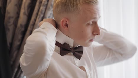 groom man adjusts bow tie, preparing to go to the bride, businessman in white shirt, wedding day