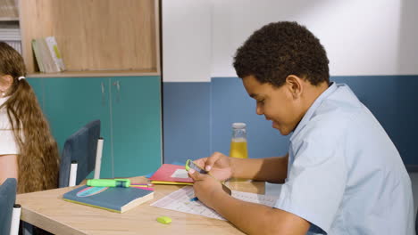 Side-View-Of-Student-Sitting-At-Desk-In-English-Classroom-While-Using-The-Smartphone