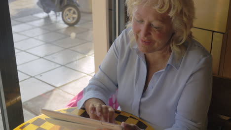 mujer anciana trabajando con una tableta en un café
