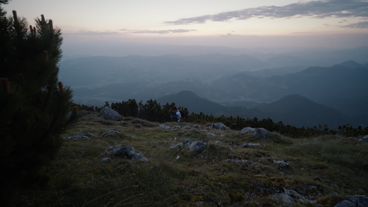 una toma del valle desde la montaña peca, el caminante pasó a lo lejos con bastones de senderismo temprano en la mañana antes del amanecer