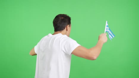 Rear view of a man waving a greek pennant
