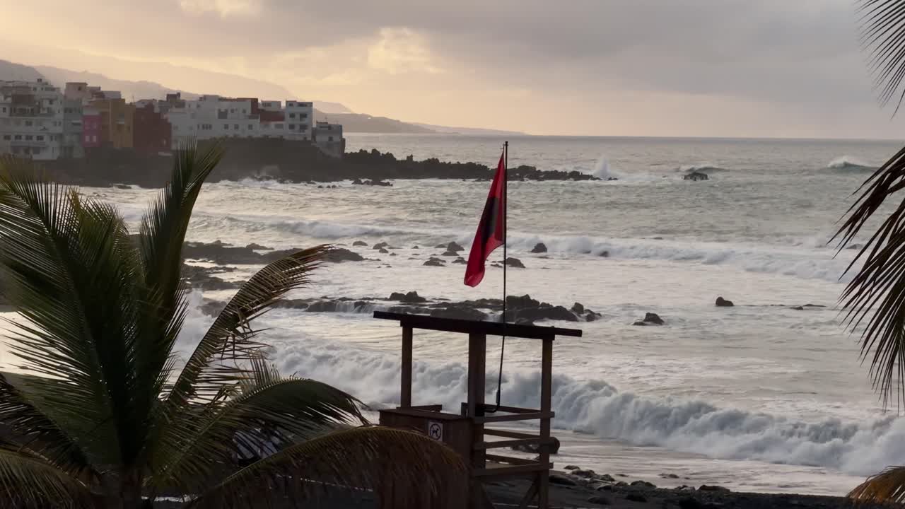 Praia de Tenerife com bandeira vermelha, ondas agitadas, cena de pôr do sol melancólico