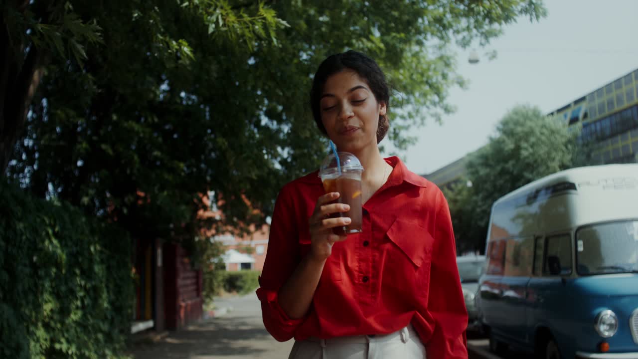 mujer disfrutando de una bebida en una calle de la ciudad