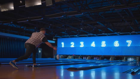 Ein-Mann-In-Einer-Bowlingbahn-Wirft-In-Zeitlupe-Einen-Ball-Und-Wirft-Kegel-Um.-Bowling-Spielen.-Bälle-Auf-Den-Boden-Des-Bowlingclubs-Werfen