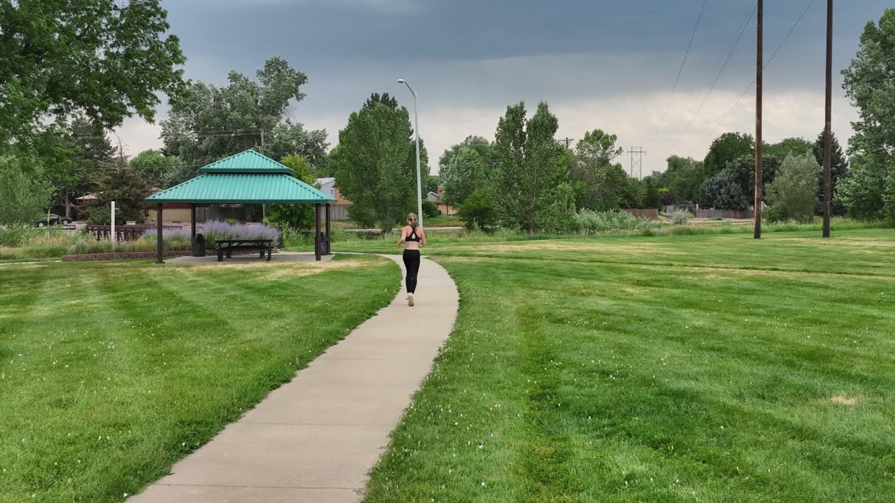 A powerful runner runs along a city pathway. An athletic woman demonstrates stamina and aerobic fitness