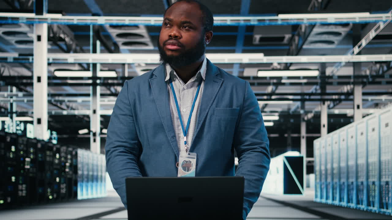 Uomo concentrato che digita sul laptop in un data center moderno