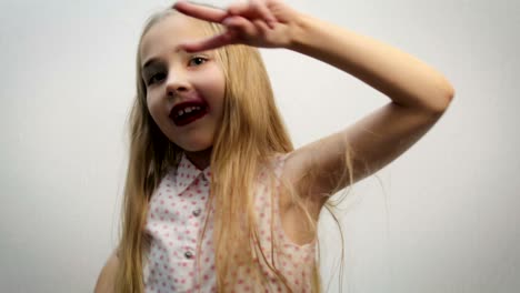 funny girl, child, blonde in a light shirt with a pink pea pattern, performing dance movements with body and hands on a white background