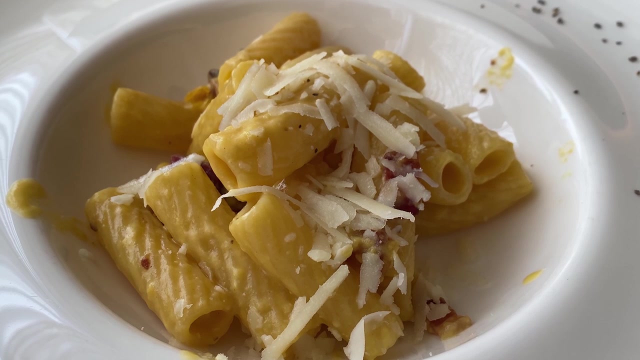 Piatto di pasta alla carbonara con maccheroni guarnito con pecorino romano