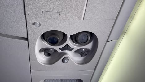 Closeup view of the hand of a white man pushing the flight attendant call button in a jet cabin