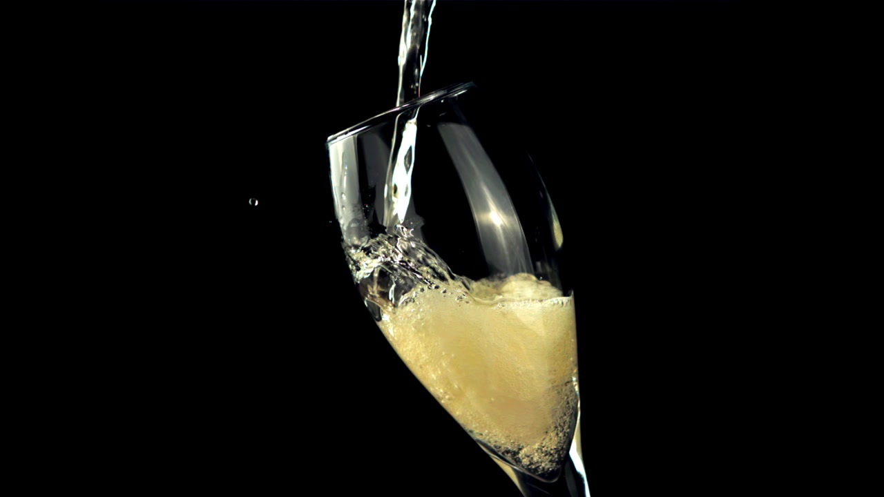 Versamento di champagne al rallentatore in un bicchiere a flûte su sfondo nero