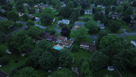middle class residential area with private pool in garden. dusk scene in quiet suburb neighborhood of america. aerial top down flyover
