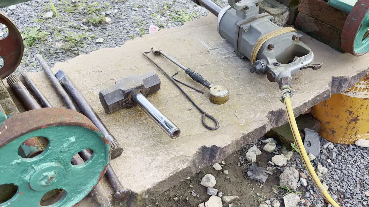 Push-in shot of heavy tools used for opening big truck tire bolts, placed with other equipment at a roadside tire repair shop in India