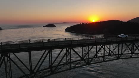toma aérea de un camión blanco que conduce sobre el parque estatal deception pass al atardecer