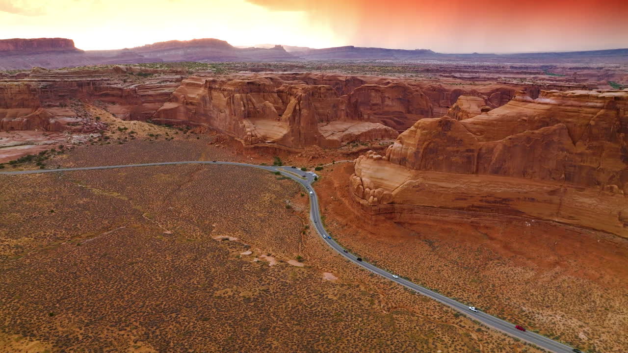 Grey road going across the plain near beautiful rocks of Zion Canyon. Breath-taking view of mountains at the backdrop of pink skies.