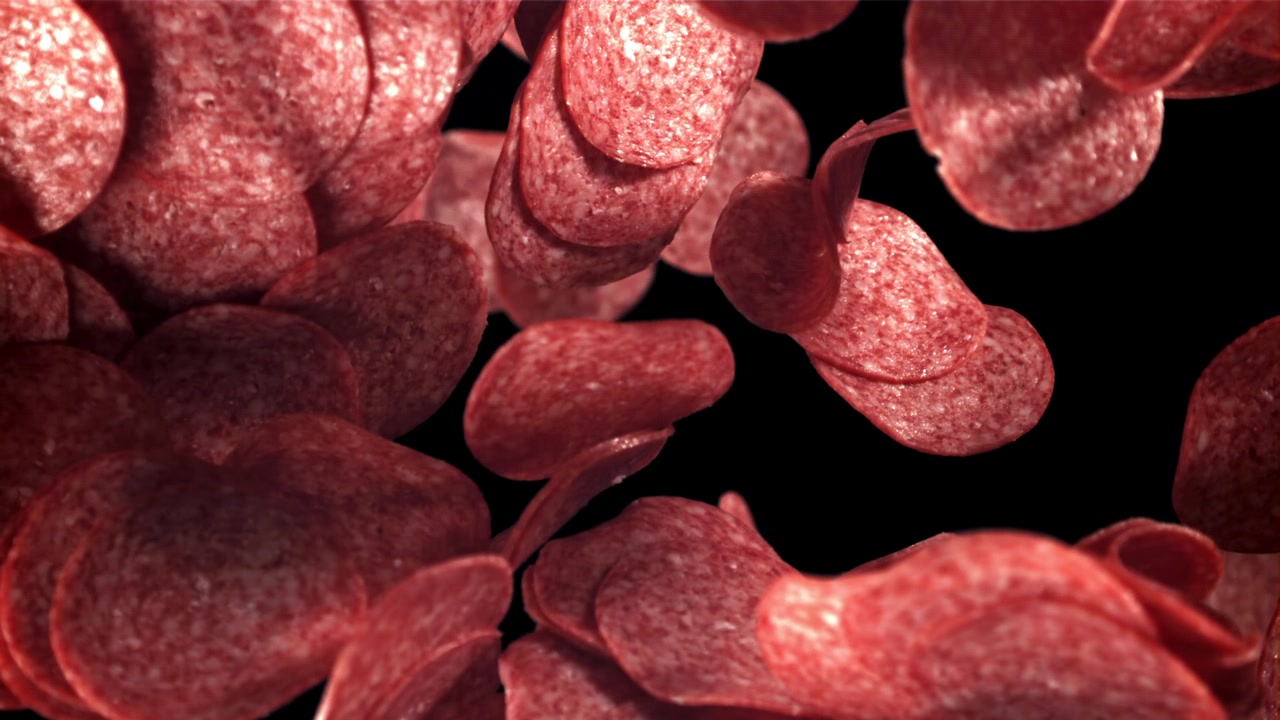 Fette di salame piccante che cadono su sfondo nero